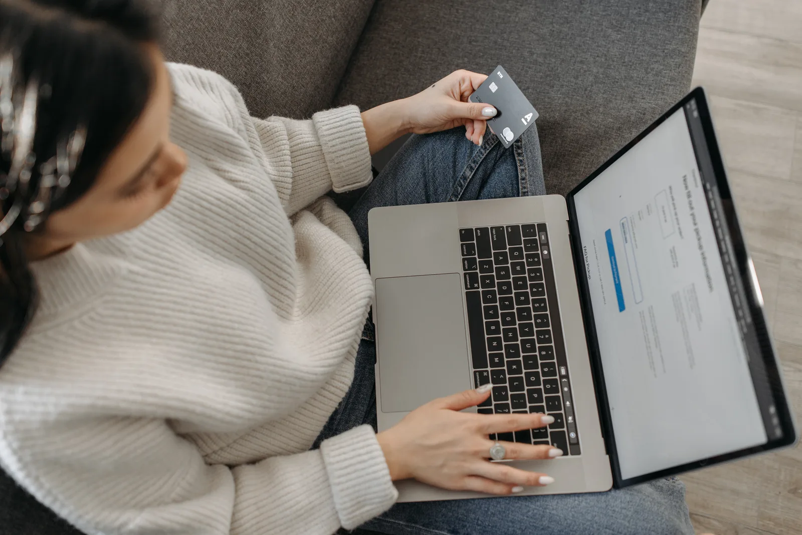 Young woman shopping online using her laptop and credit card from home.