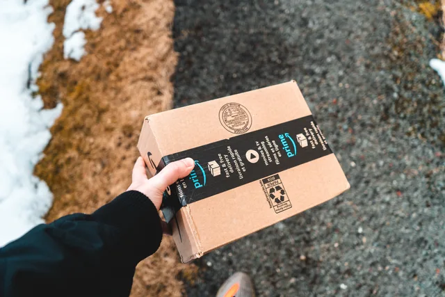 A person holding a cardboard Amazon Prime package on a snowy urban sidewalk. How platform reviews work here, with a claim ledger and gates that stay independent