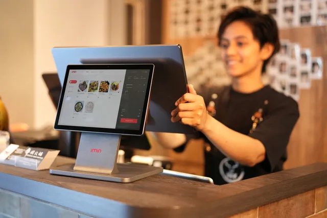 Smiling cashier using a touchscreen POS system in a modern retail environment. Investigating ecommerce platforms with dated supplier evidence and eight independent gates