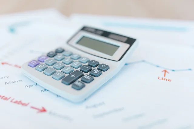 Close-up of a calculator on financial documents with graphs and analysis papers. How to compare ecommerce platform quotes with a scope sheet