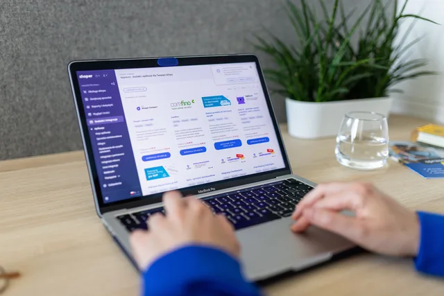 Close-up of hands on a laptop browsing an e-commerce site in a modern office. What ecommerce platform do most UK online stores use?